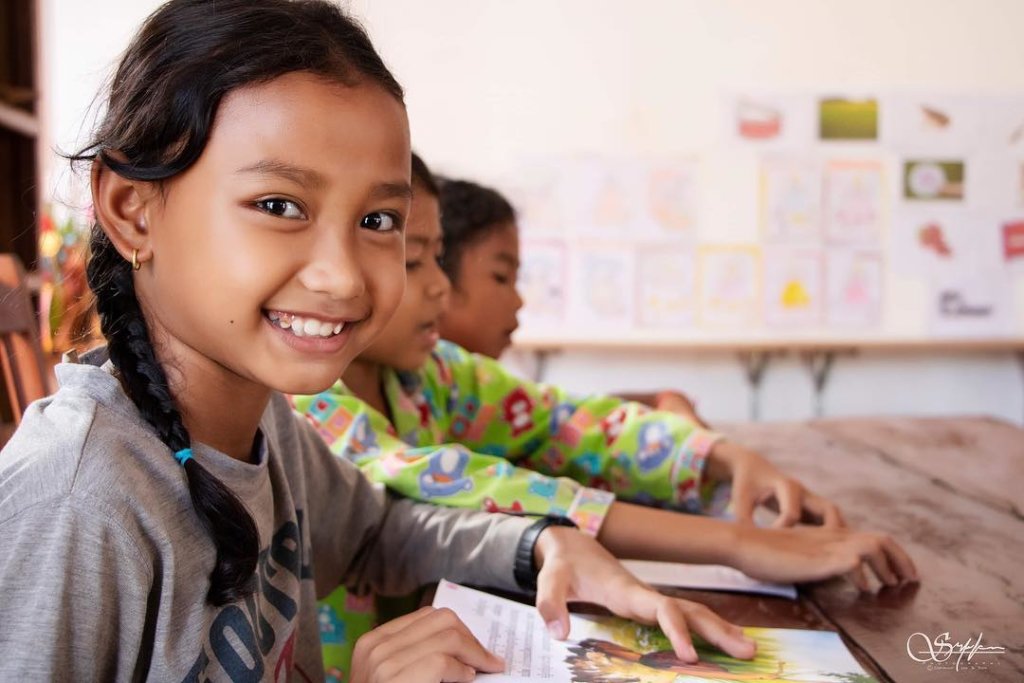 Cambodian students reading together in a bright learning space, the model behind the EDGE Worldwide Education and Pastoral Care Hub