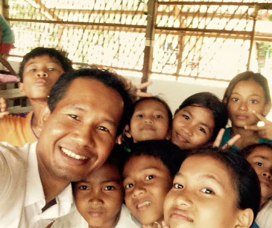 A Cambodian teacher surrounded by his students, part of the local capability EDGE Worldwide helps develop