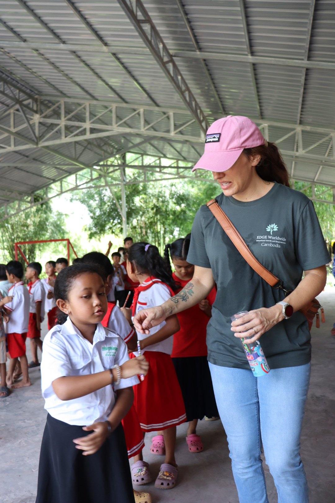 An EDGE Worldwide participant hands a pencil to a student during the Beong Touk activities