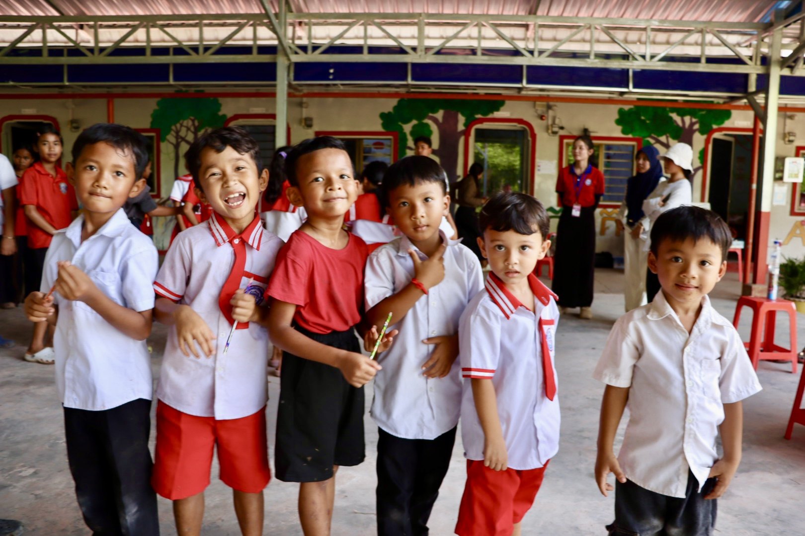 Students holding pencils gather in a school courtyard during the Beong Touk activities