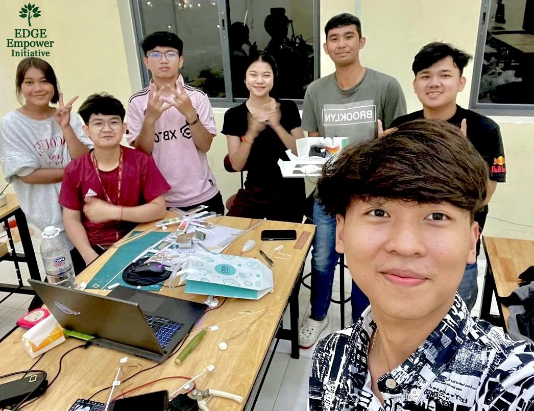 Students gathered around a classroom table with a laptop and model-making materials