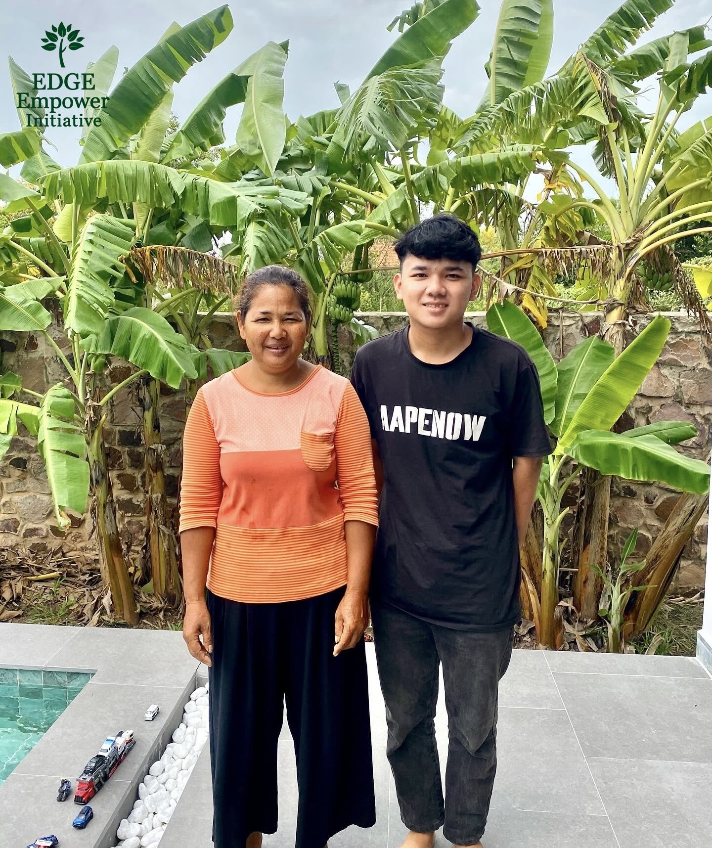 Mony standing beside a woman outdoors in front of banana plants
