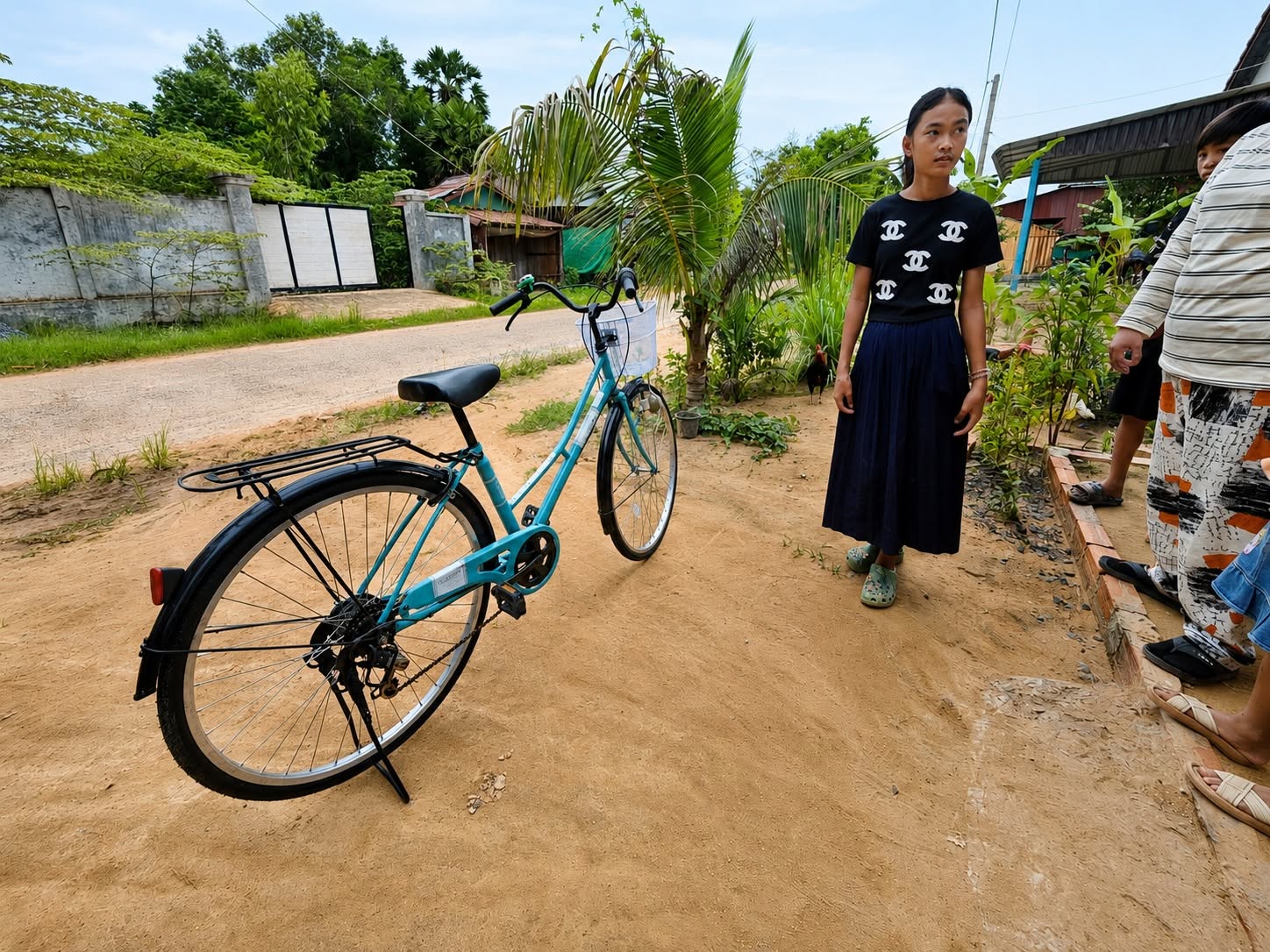 Sana standing beside a blue bicycle outdoors in Cambodia.