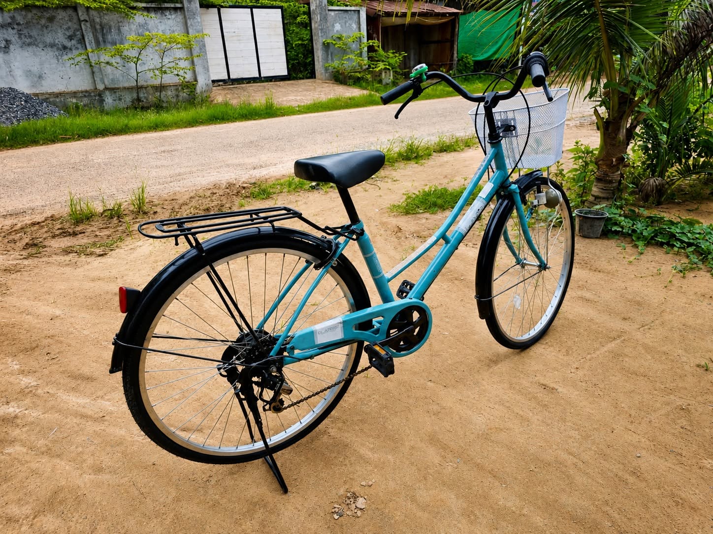 Blue bicycle with a front basket and rear carrier beside a road in Cambodia.